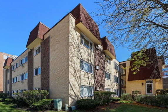 Front view of a multi-story apartment building with brick exterior and brown accents.