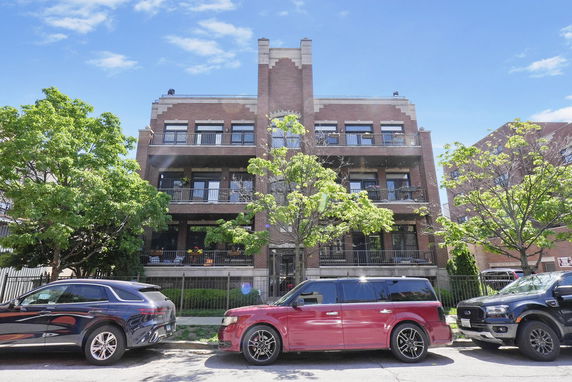 Front view of a three-story brick building with balconies.