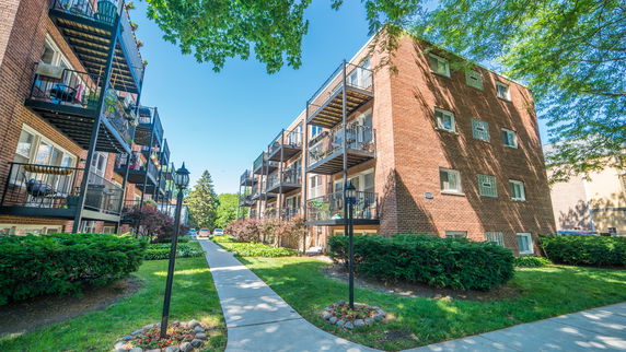 Front view of a multi-story brick apartment building with balconies.