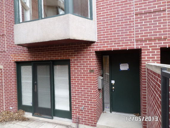 Front view of a brick building with a balcony and entrance door.