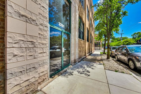 Front view of a building with tall glass windows and a brick facade.