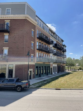 Front view of a multi-story brick apartment building with balconies.