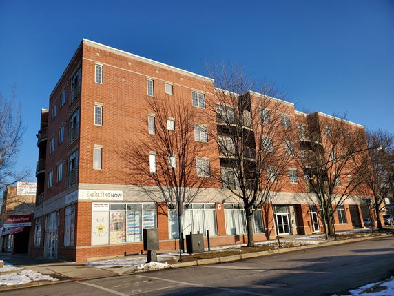 Front view of a multi-story brick building with large windows and balconies.