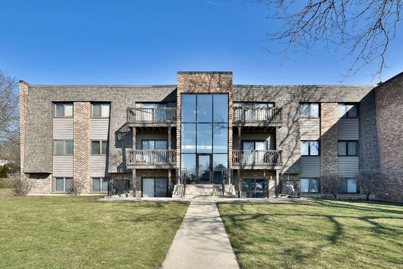 Front view of a multi-story residential building with balconies and large windows.