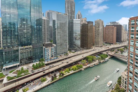 Panoramic view of a cityscape with tall buildings and a river with boats.