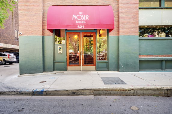 Front view of a building with a red awning and double glass doors.