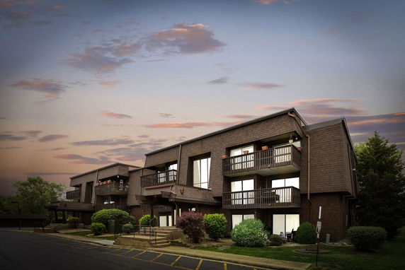 Front view of a multi-story building with balconies and a sloped roof.