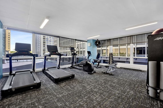 Indoor gym area with exercise equipment and large windows.