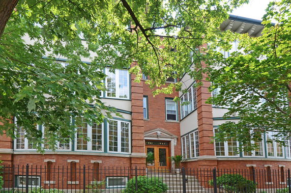 Front view of a large brick building with large windows and a central entrance.
