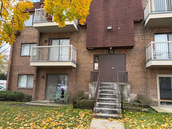 Front view of a three-story brick apartment building with balconies.