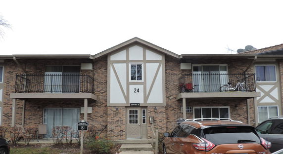 Front view of a two-story brick apartment building with balconies.