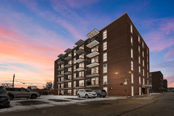 Front view of a multi-story brick apartment building with balconies.