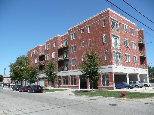 Front view of a multi-story brick apartment building with balconies.