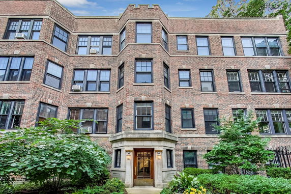 Front view of a multi-story brick apartment building with multiple windows.