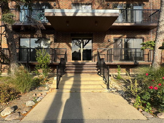 Front view of a multi-story brick building with balconies and a central entrance.