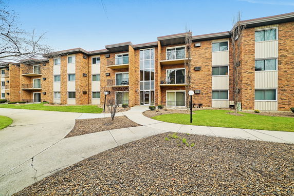 Front view of a multi-story apartment building with brick exterior and multiple balconies.