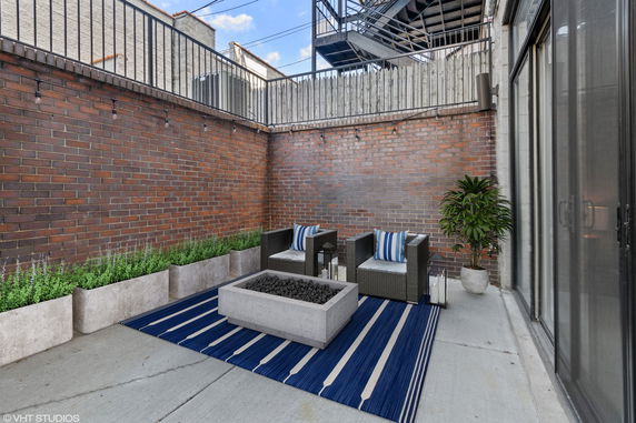Outdoor patio area with brick walls, seating, and a fire pit.