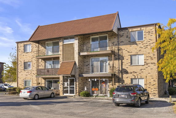 Front view of a three-story apartment building with balconies and a sloped roof.