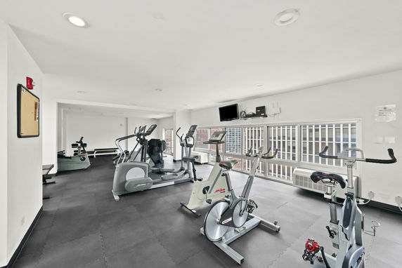 Indoor gym area with exercise equipment and large windows.