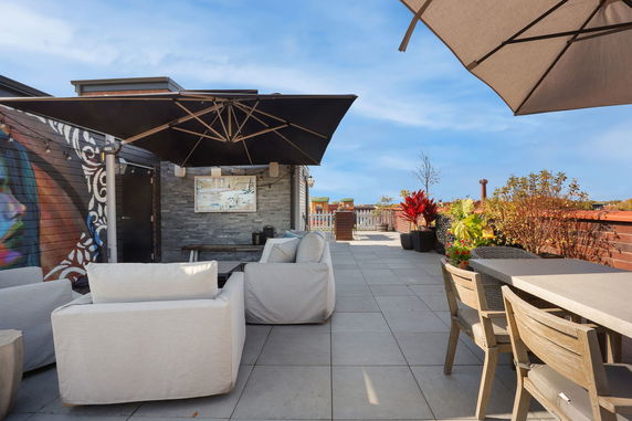Rooftop area with seating, umbrellas, and decorative plants.