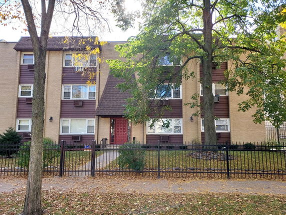 Front view of a multi-story residential building with a red door and brick exterior.