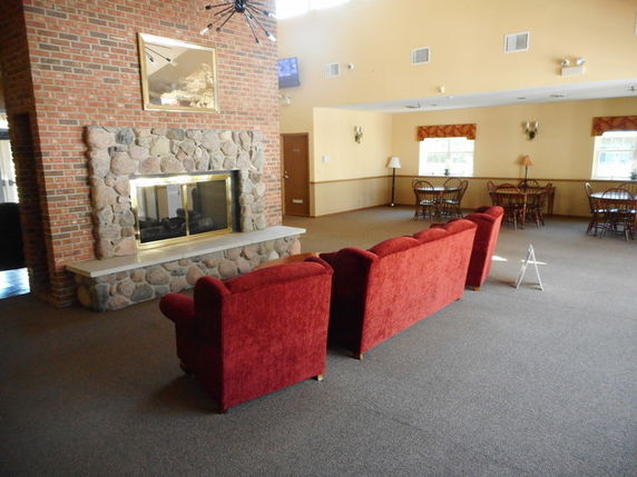 Interior view of a clubhouse with red sofas and a stone fireplace.
