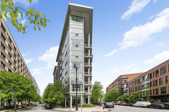 Front view of a modern multi-story building with glass windows on a city street.