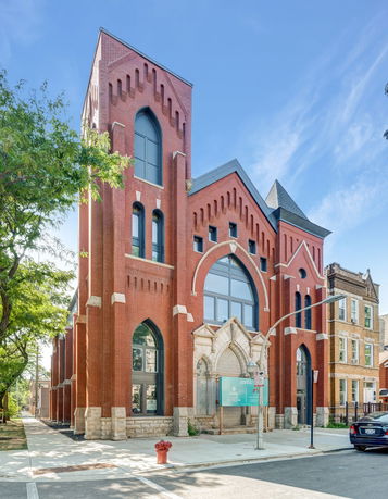 Front view of a red brick building with arched windows and detailed masonry.
