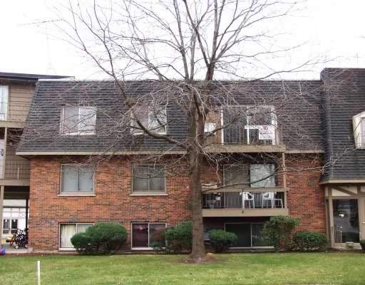 Front view of a multi-story brick apartment building with several balconies.