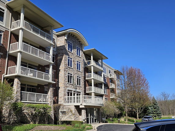 Front view of a multi-story building with multiple balconies and stone cladding.
