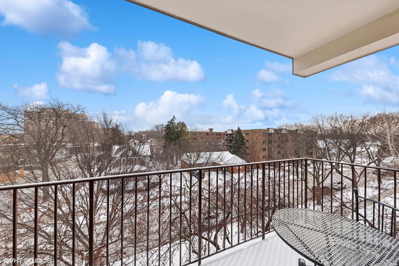 Panoramic view from a balcony overlooking a snowy landscape with buildings and trees.