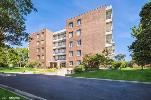 Front view of a multi-story brick apartment building with balconies.