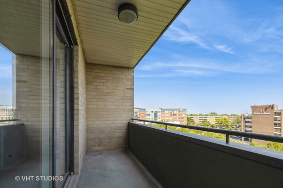 View from a building balcony overlooking other buildings and a clear blue sky.