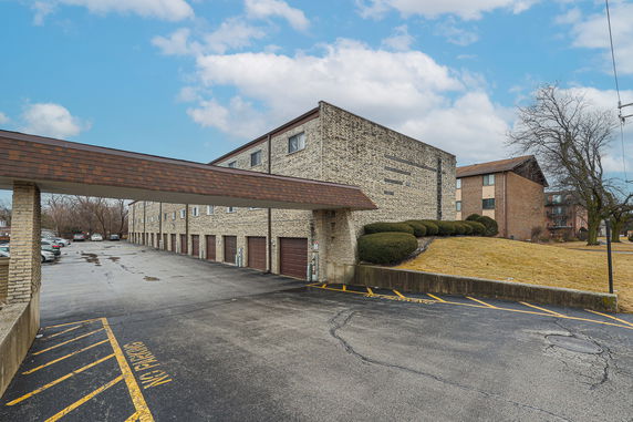 Front view of a multi-story building with a covered parking area beneath.