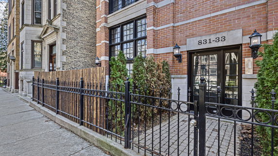 Front view of a brick building with a gated entrance and large windows.