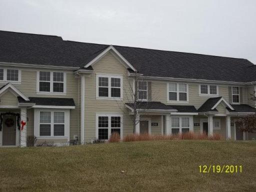 Front view of a row of two-story townhouses with light-colored siding and dark roofs.