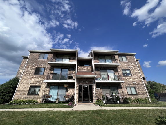 Front view of a three-story apartment building with balconies.