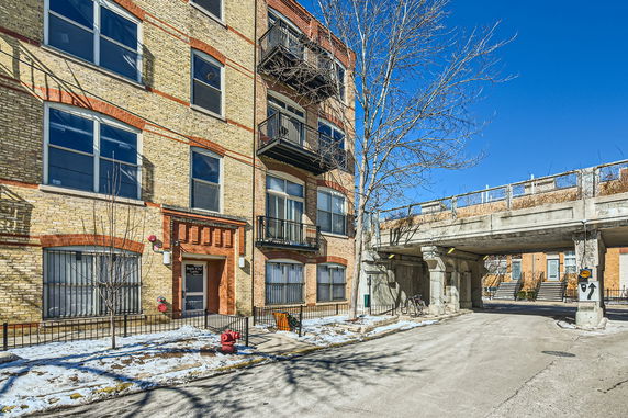 Front view of a multi-story brick building with balconies and large windows.