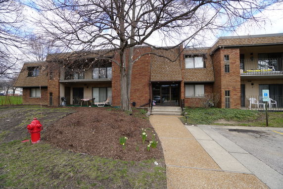 Front view of a two-story brick apartment building with balconies and a central entrance.