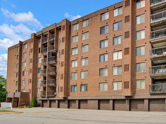 Front view of a multi-story brick apartment building with balconies.