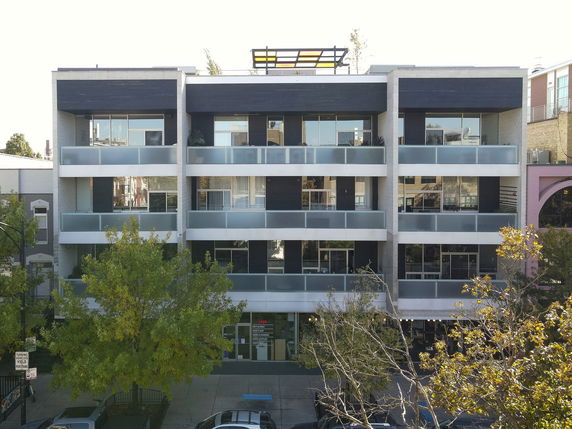 Front view of a modern multi-story apartment building with glass balconies.