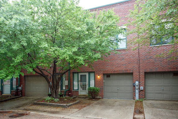 Front view of a brick townhouse with double garages and a central entrance.