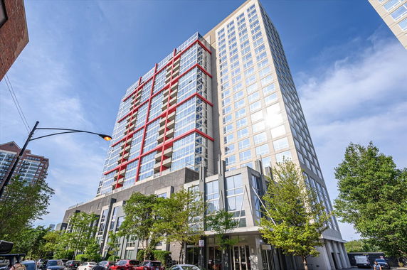 Front view of a modern high-rise building with glass windows and red accents.