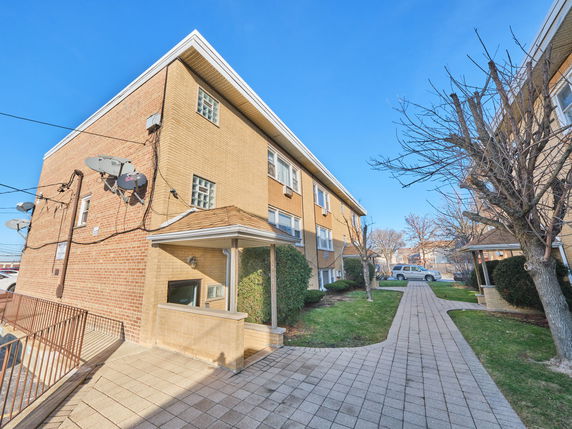 Front view of a multi-story brick building with satellite dishes attached.