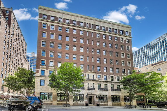 Front view of a multi-story brick building with multiple windows and decorative elements.