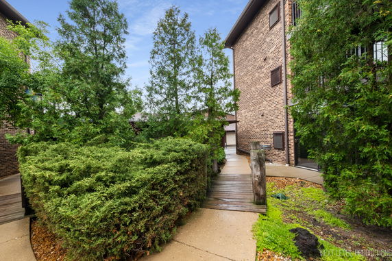 Side view of a multi-story brick building with pathway and greenery.