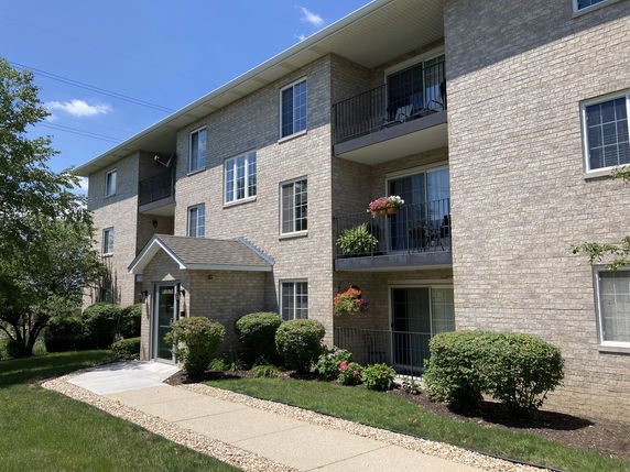 Front view of a multi-story brick apartment building with balconies.