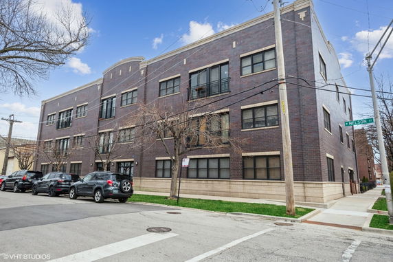 Front view of a three-story brick building on a street corner.