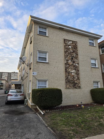 Front view of a three-story brick building with decorative stone panel.