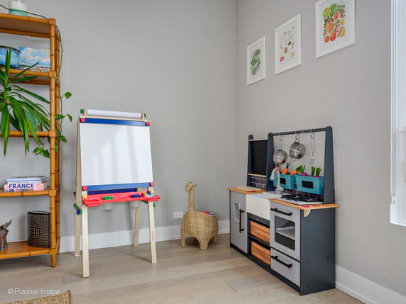 Indoor children's play area with a small kitchen set and art easel.